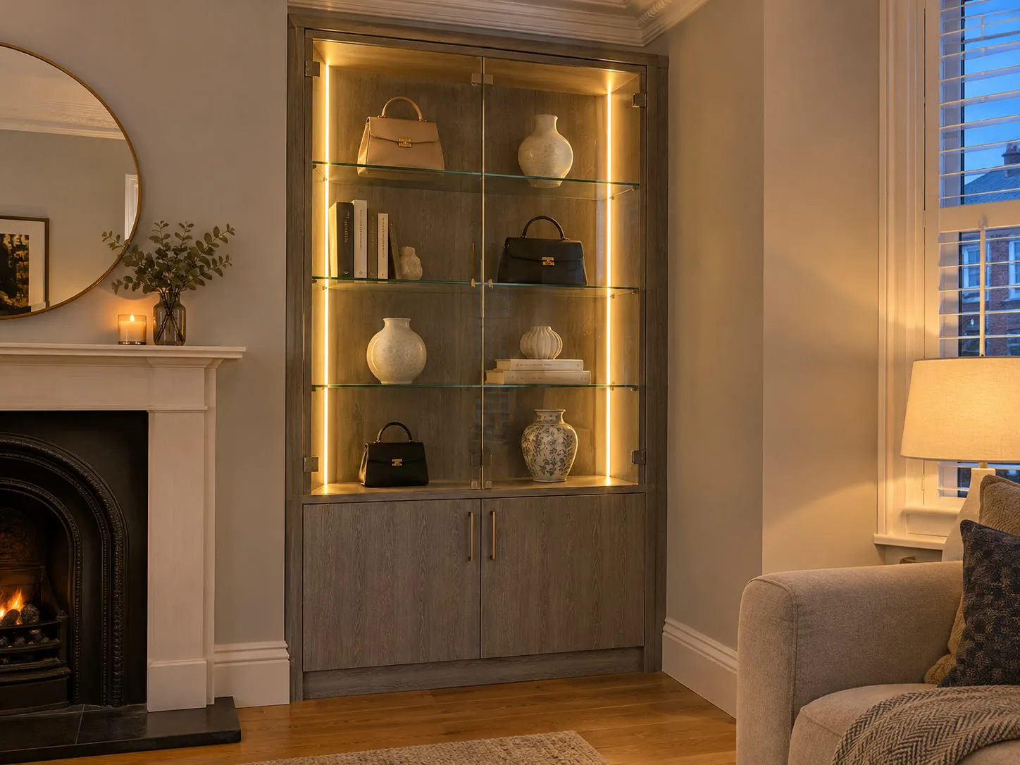 Illustration: alcove display cabinet in grey oak with glass shelves and warm LED strips beside a fireplace