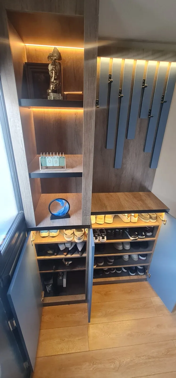 Open shoe shelves inside a hallway cabinet, lit from above