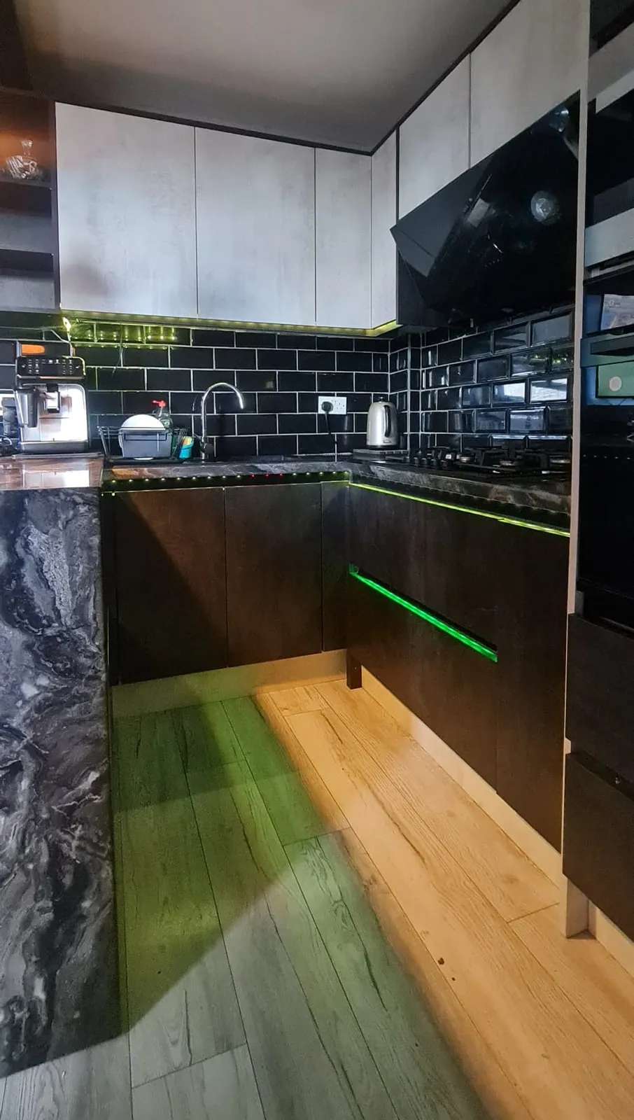 Black kitchen units with a marble-effect worktop and LED strips under the cabinets, Handsworth
