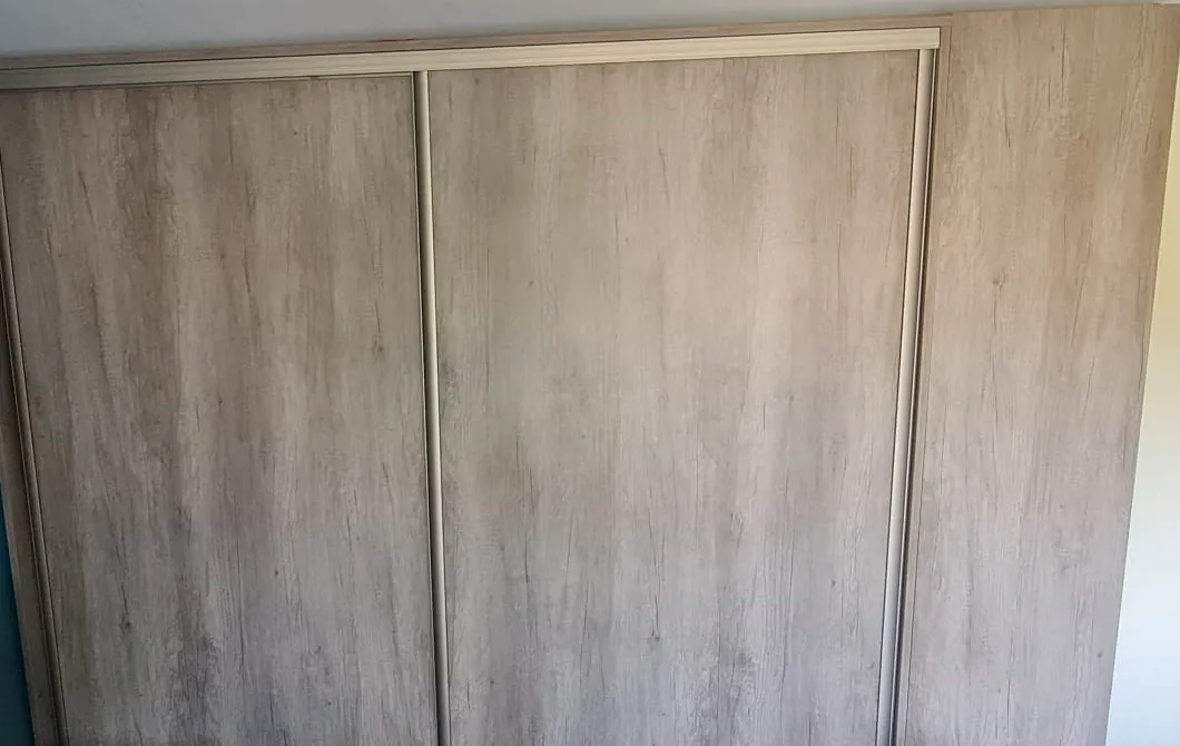 Floor-to-ceiling sliding wardrobe with two grey oak doors and a matching end panel